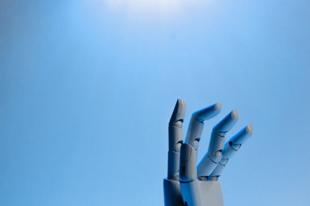 about-img-01 Robotic hand with articulated fingers reaching towards the sky on a blue background.